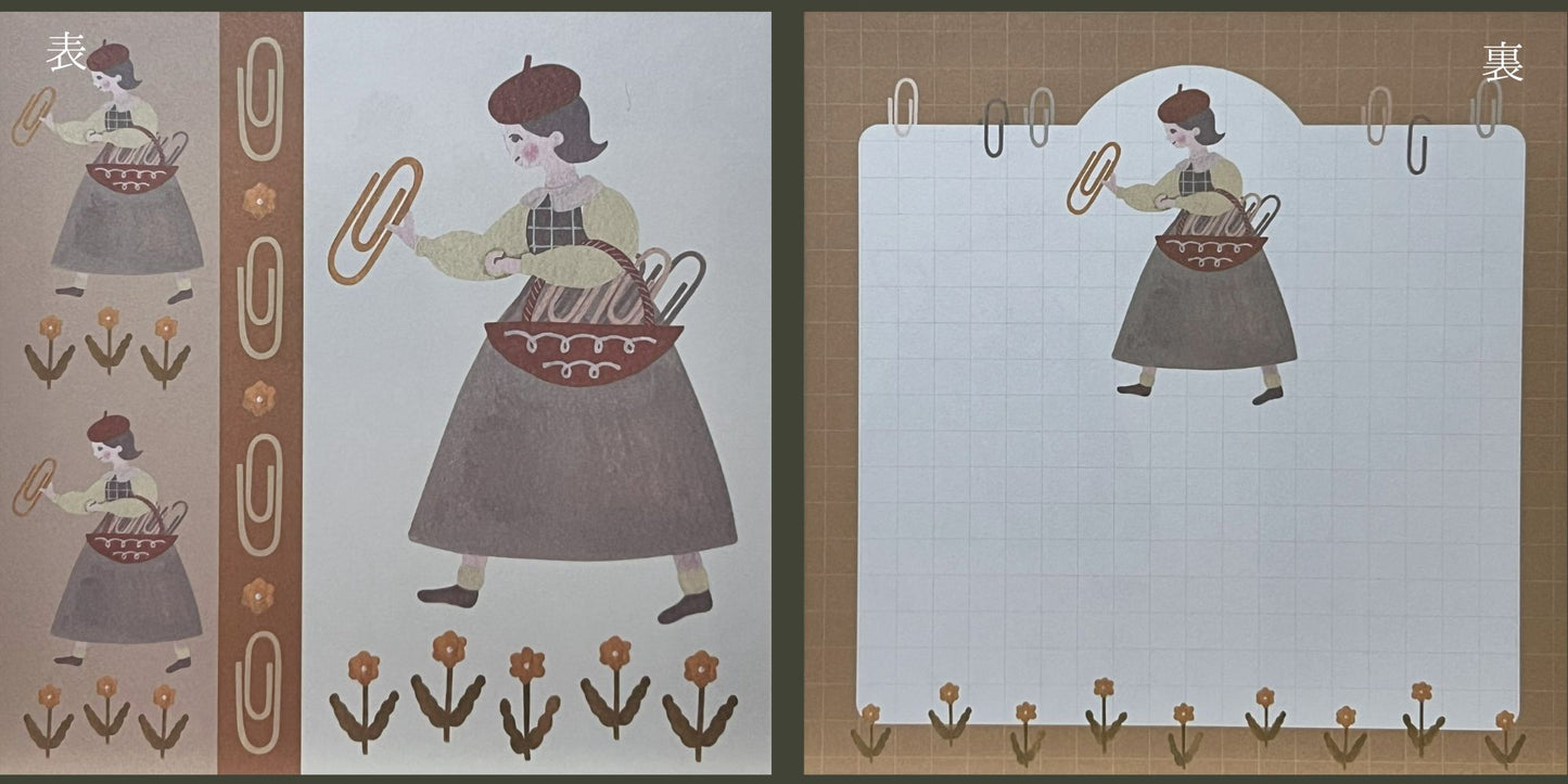 鉛筆に囲まれた森の中で読書する少女が描かれた、伊野あゆみさんの両面ましかくメモ。
A double-sided square memo pad by Ayumi Ino, featuring a girl reading among pencil trees in a forest-like scene.