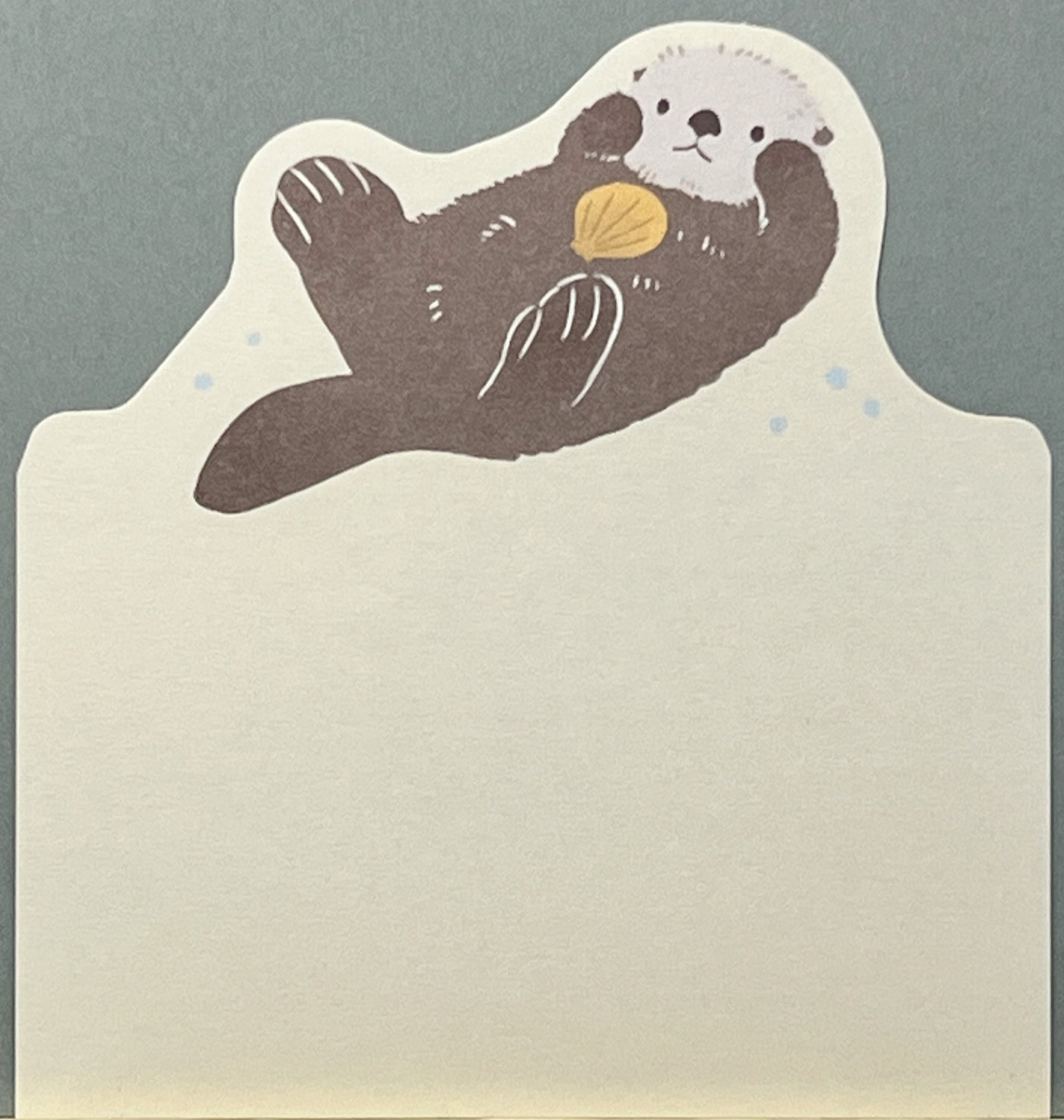 貝をかかえてぷかぷか浮かぶラッコが描かれた、ダイカット型の癒し系メモ帳。
A die-cut memo pad featuring a sea otter floating with a shell in gentle, soothing colors.